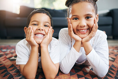 Buy stock photo Portrait of two mixed race young siblings lying on the floor together at home and smiling. Little hispanic boy and girl having fun in the lounge at home