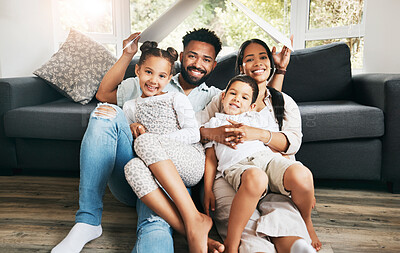 Buy stock photo Portrait of a hispanic family holding a cardboard shaped roof at home. Mixed race family covered by a cardboard roof at in the lounge while sitting on the floor