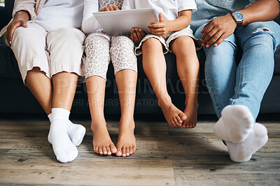 Buy stock photo Closeup of a family sitting on a sofa using a tablet in the lounge at home. Family feet relaxing while sitting on a couch during the day