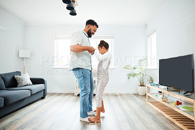 Buy stock photo A mixed race father dancing with his daughter while she stands on his feet in the lounge at home. Hispanic male having fun with his daughter in the living room