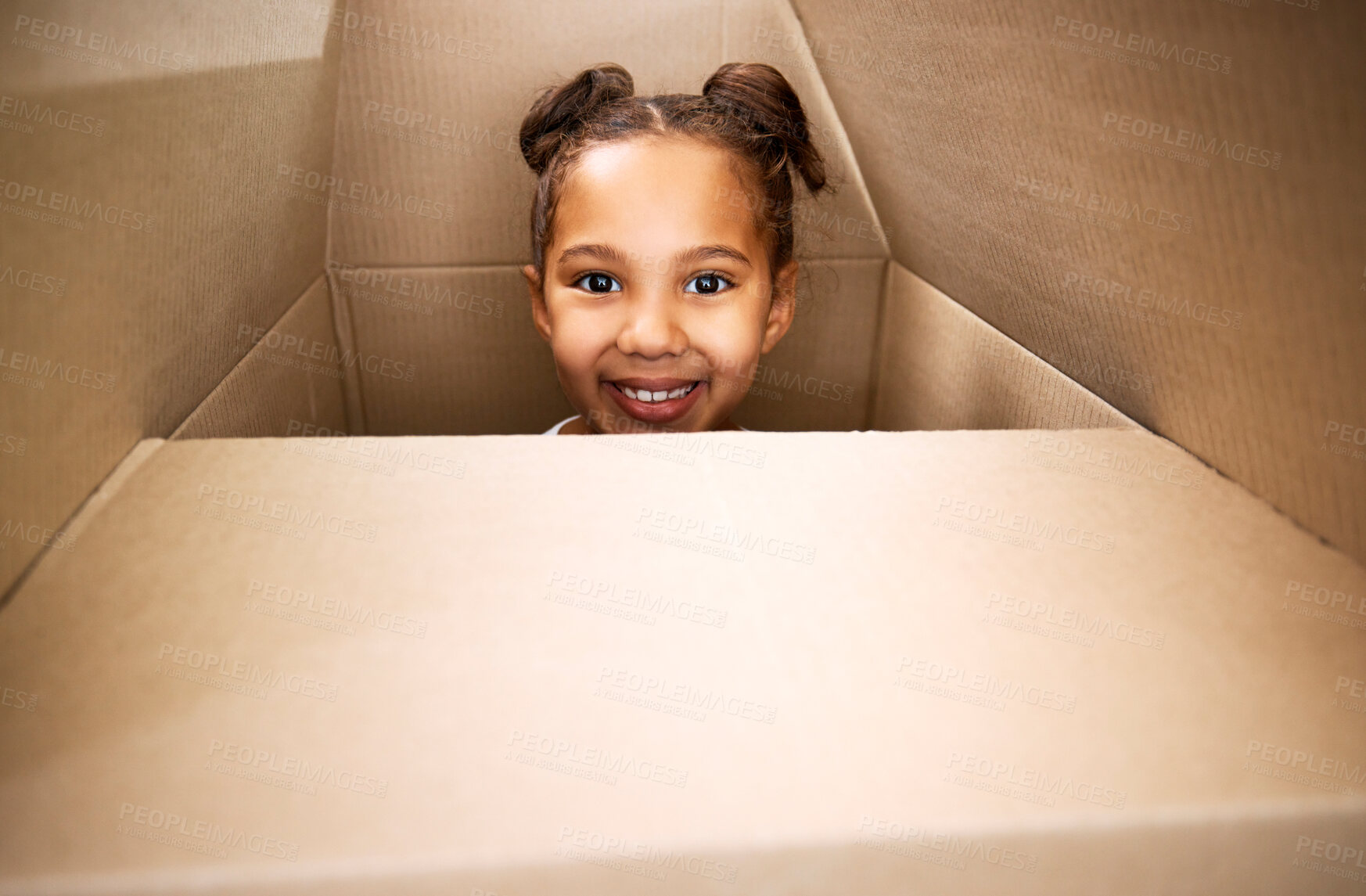 Buy stock photo Portrait of a cute little hispanic girl playing with a cardboard box in a new apartment. Cute mixed race girl hiding in a box and smiling in a house. Relocation and moving day of big family