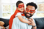 Hispanic father and son dressed up like superheroes and playing in the lounge at home. Mixed race boy and man playing and having fun