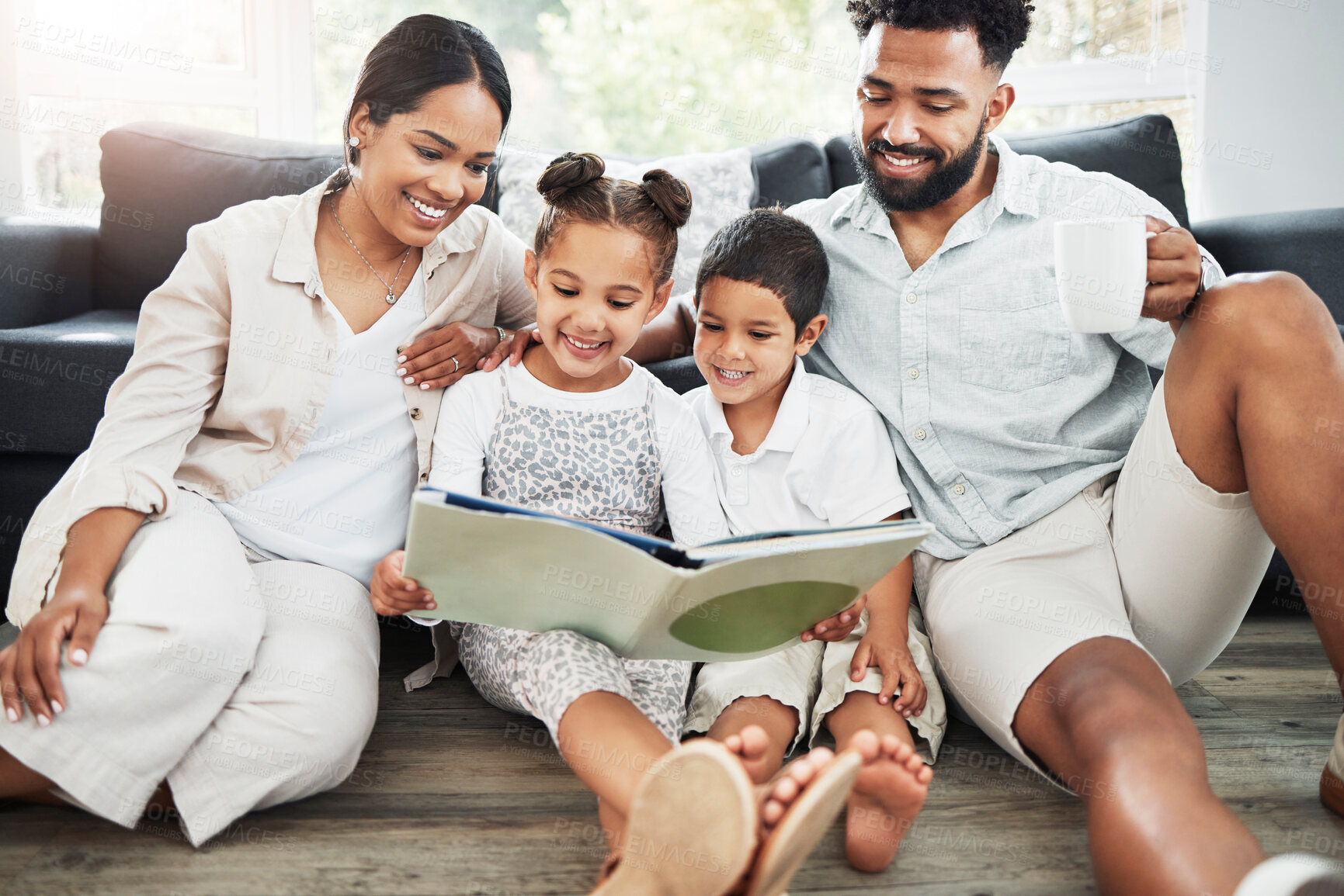 Buy stock photo Mixed race family reading a book together on the floor at home. Hispanic mother and father teaching their little son and daughter how to read. Brother and sister learning to read with their parents