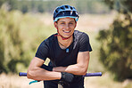 Portrait of a handsome man wearing a helmet and taking a break from cycling on his bicycle outside. Male athlete exercising in a park. Sporty male training on his bike. Keeping his heart healthy