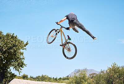 Buy stock photo Man showing his cycling skills while out cycling on a bicycle outside. Adrenaline junkie practicing a dirt jump outdoors. Male wearing a helmet doing tricks. Unrecognizable passionate guy having fun  