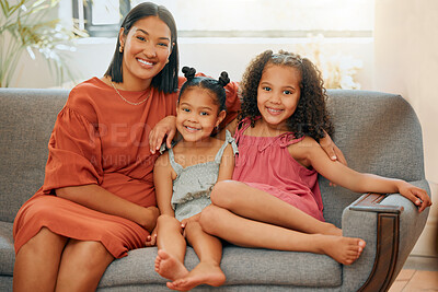 A happy mixed race family of three relaxing in the lounge and sitting on the couch together. Loving black single parent bonding with her daughters while relaxing on a sofa at home
