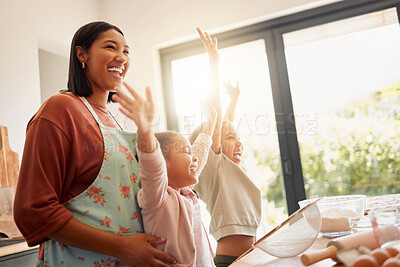 Females only, happy mixed race family of three cooking in a messy kitchen together. Loving black single parent bonding with her daughters while teaching them domestic skills at home