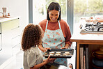 Two females only cooking and having fun in a kitchen together. Young mixed race single parent bonding with her daughter while teaching her domestic skills at home