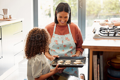 Buy stock photo Two females only cooking and having fun in a kitchen together. Young mixed race single parent bonding with her daughter while teaching her domestic skills at home