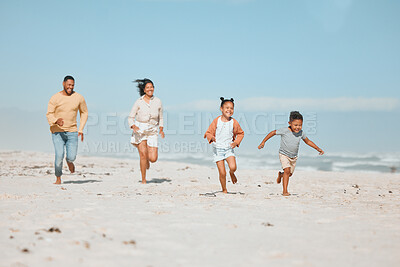 Buy stock photo Cheerful young mixed race family running on the beach, Happy mother and father with two children having fun during summer holiday. Playful casual family racing on sandy beach enjoying time together