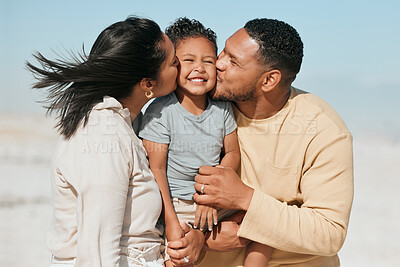 Buy stock photo Happy mixed race family standing on the beach. Loving parents kissing adorable little son on the cheeks showing love and affection while enjoying beach vacation