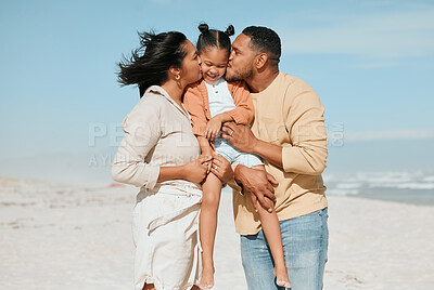 Buy stock photo Happy mixed race family standing on the beach. Loving parents kissing adorable little daughter on the cheeks showing love and affection while enjoying beach vacation