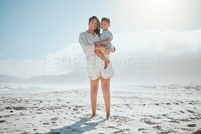 Buy stock photo Portrait of loving young mixed race mother holding her adorable little son while smiling and looking at the camera on a windy day at the beach. Mother and son spending time and having fun together while on holiday