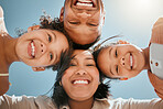 Portrait of a happy young mixed race family standing together in huddle smiling and looking down at camera on a sunny day. Faces of cheerful parents and two daughters embracing each other from below