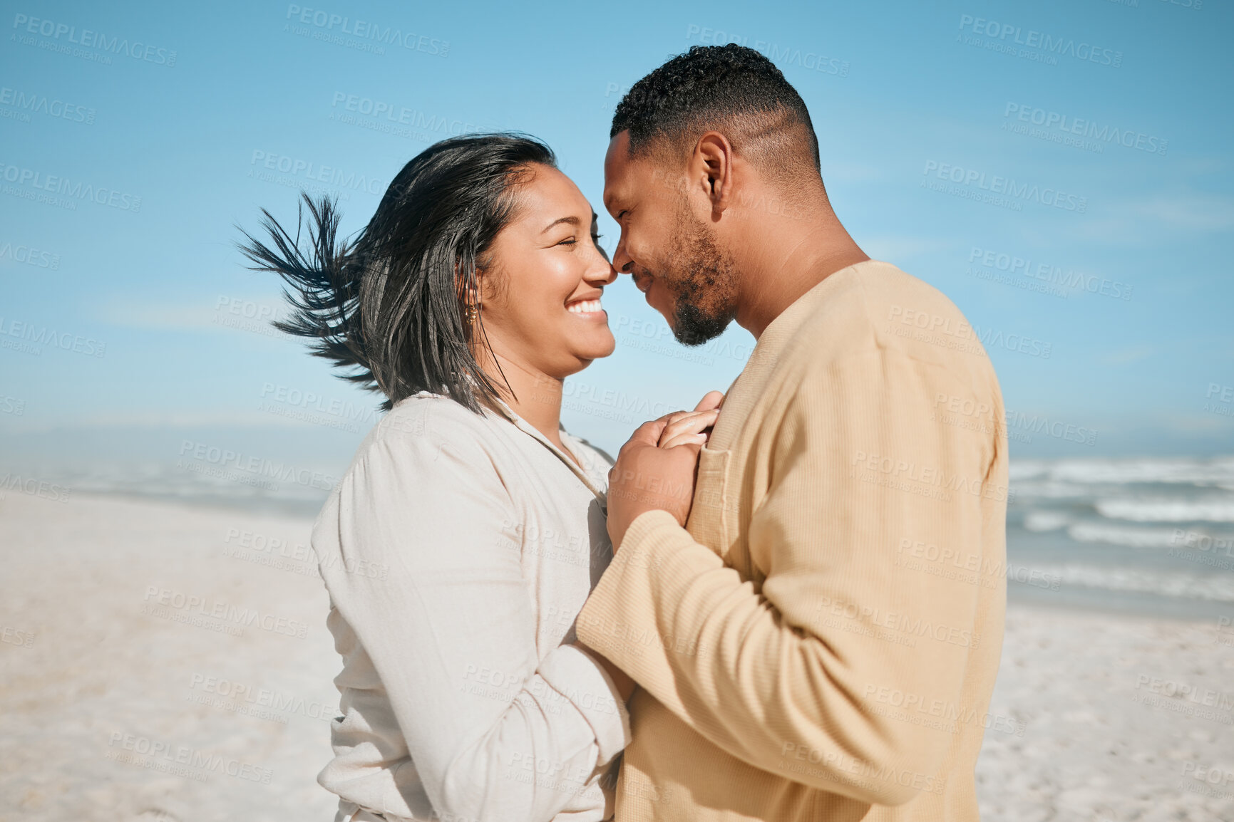 Buy stock photo Loving young mixed race couple touching noses while dancing on the beach. Happy young man and woman in love  enjoying romantic moment while on honeymoon by the sea