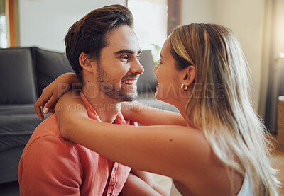 Buy stock photo Close up of happy young caucasian couple sitting together and share romantic intimate moment at home. Young woman putting her arms around boyfriend while they look into each others eyes
