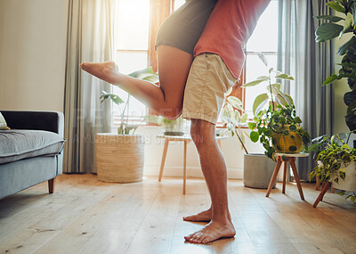 Buy stock photo Close up of young boyfriend in shorts lifting girlfriend up in modern apartment. Romantic young couple hugging in living room and enjoying passionate dance at home