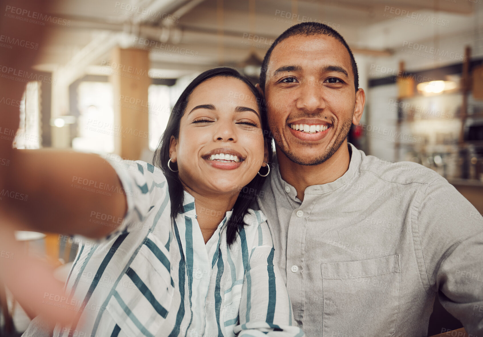 Buy stock photo Close up of young woman holding mobile phone while taking a selfie with her boyfriend in a cafe. Loving mixed race couple looking happy while sitting together on a date