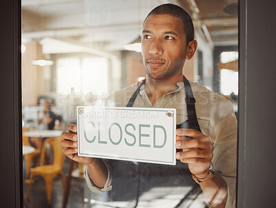 Businessman hanging a closed sign in his shop door. Bistro boss closing his restaurant. Shop assistant closing the store alone. Business owner advertising that his restaurant is closed.