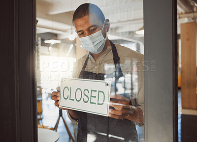 Business owner closing their shop in the pandemic. Boss hanging a closed sign in shop door in quarantine. Small business owner advertising that his restaurant is closed. Businessman wearing a mask