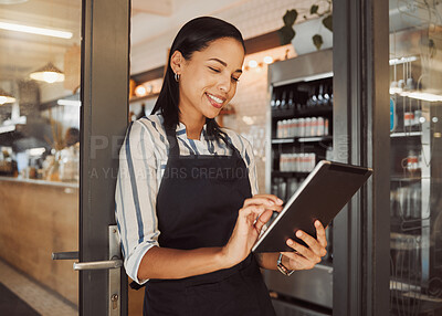 Businesswoman using a digital tablet in her restaurant. Cafe owner using an online app in her shop entrance. Confident business owner using a wireless device in her grocery store.