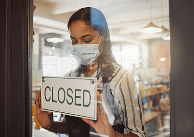 Businesswoman closing her shop in the pandemic. Business owner hanging a closing sign in her shop entrance. Small business owner closing her store in covid lockdown. Boss wearing a mask in her store