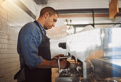 Focused barista making a cup of coffee. Barista making a cup of cappuccino. Coffeeshop assistant preparing a cup of espresso using the coffee machine. Mixed race businessman making a cup of coffee