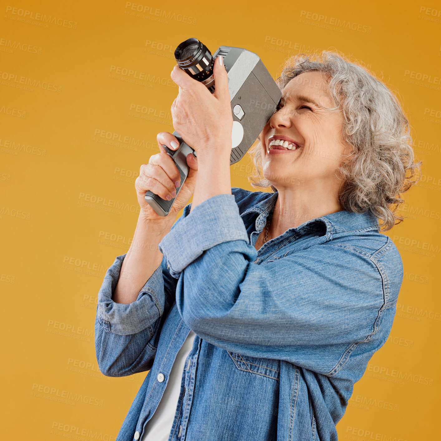 Buy stock photo One happy caucasian woman standing against a yellow background in a studio and taking a picture on a camera. Confident cheerful caucasian lady holding a camera and taking a photograph. Smile and pose