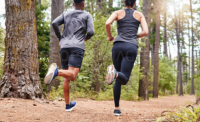 Buy stock photo Fit male and female athletes running in nature. Young sportspeople couple out for a workout in the forest. Keeping fit and staying healthy together