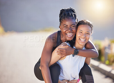 Buy stock photo Two fit playful women wearing sportswear while out for a run outdoors. Cheerful young sportswoman giving her friend a piggyback ride on her back while exercising on a road