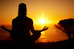Rearview silhouette yoga woman meditating with legs crossed for outdoor practice in remote nature. Mindful person sitting alone and balancing for mental health at sunset. Serene and zen in lotus pose