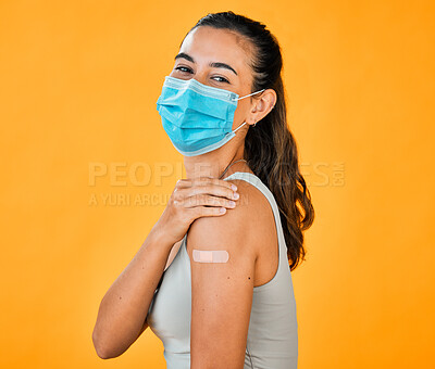 Buy stock photo Mixed race covid vaccinated woman showing plaster on arm, wearing surgical face mask. Portrait of hispanic woman isolated against yellow studio background with copyspace. Protected with corona vaccine