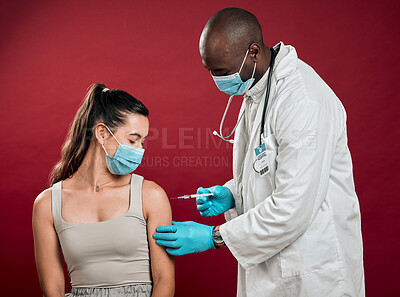 Buy stock photo African american doctor giving covid vaccine to mixed race woman and wearing surgical face mask. Hispanic patient getting corona injection from physician against red studio background with copyspace