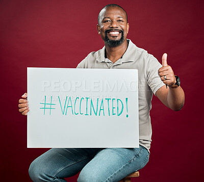 Buy stock photo African american covid vaccinated man showing thumbs up sign and symbol and holding poster. Portrait of black man isolated on red studio background with copyspace. Promote corona vaccine and motivate