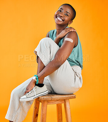 Buy stock photo African american covid vaccinated woman showing plaster on arm and smiling. Portrait of black model isolated against yellow studio background with copyspace. Protected from corona in vaccine injection