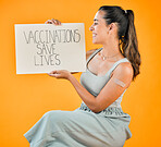 Mixed race covid vaccinated woman showing plaster on arm and holding poster. Smiling hispanic woman isolated against yellow studio background with copyspace. Model promoting corona vaccine with sign