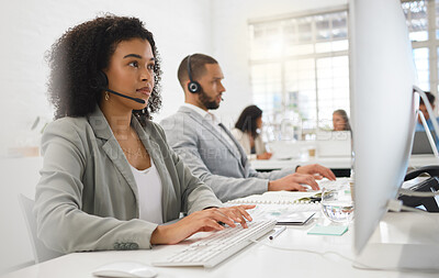 Buy stock photo Young mixed race female call center agent answering calls while wearing a headset at work. Hispanic businesswoman with a curly afro talking on a call while typing on a desktop computer at a desk in an office