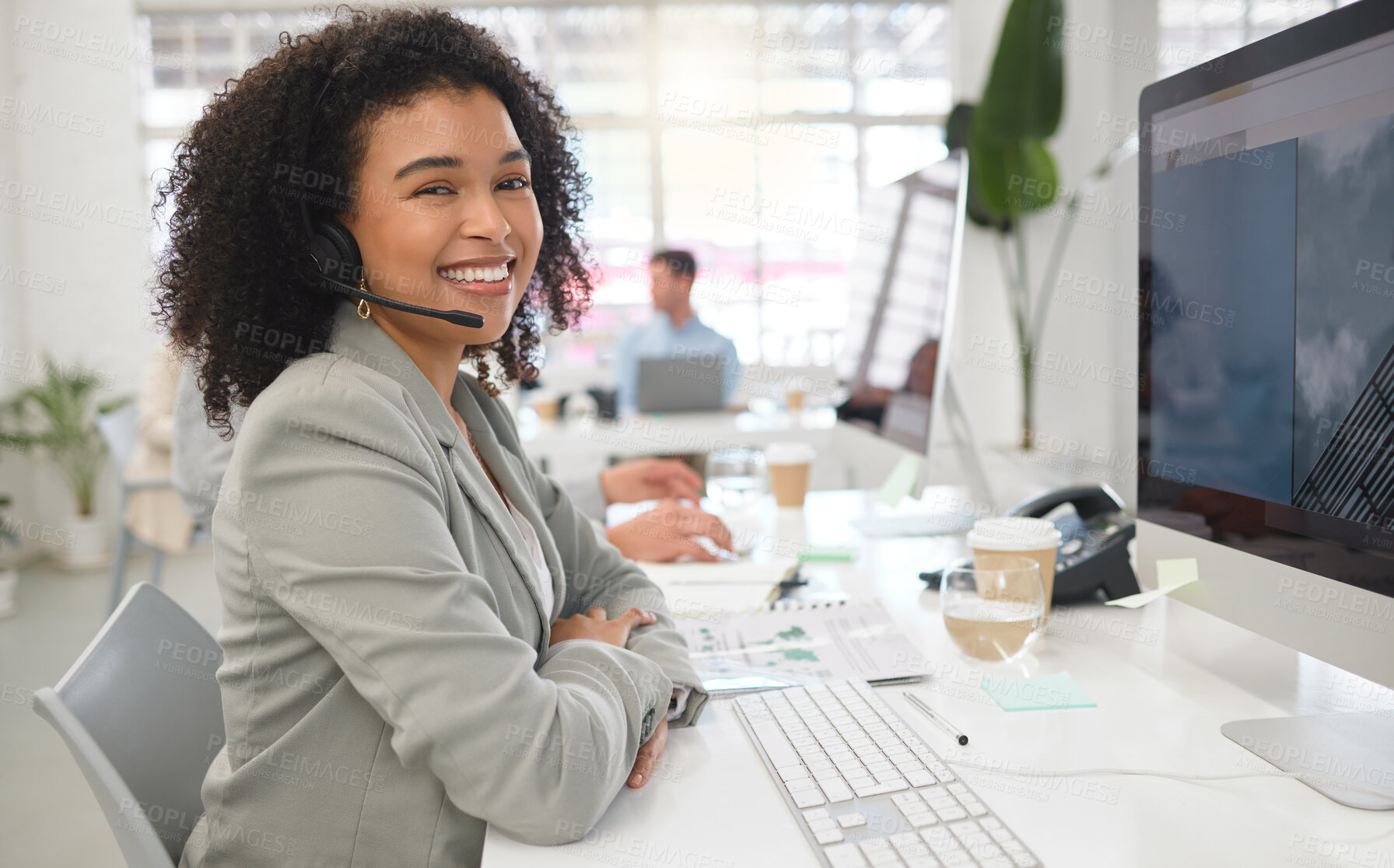 Buy stock photo Portrait of a young happy mixed race female call center agent answering calls while wearing a headset at work. One hispanic businesswoman with a curly afro talking on a call while using a desktop computer at a desk in an office