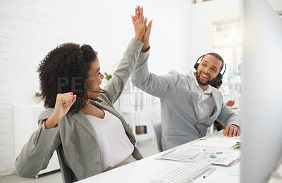 Buy stock photo Two young happy mixed race call center agents giving each other a high five while answering calls in an office at work. Joyful hispanic customer service workers joining hands in motivation and support while working together