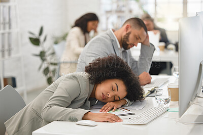 Buy stock photo Young mixed race businesspeople sleeping at their desks while working in an office at work. Hispanic business professionals taking a nap while working together