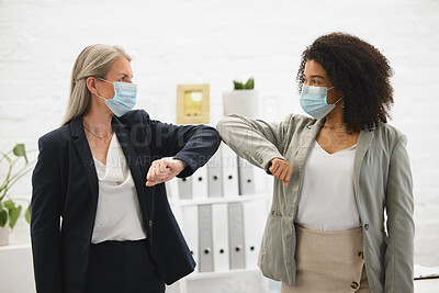 Buy stock photo Two diverse colleagues talking and greeting each other with their elbows while wearing masks to protect from infection of a virus. Businesswomen joining their elbows to greet in an office at work