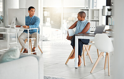 Buy stock photo Two businesspeople talking while working in an office together. Young asian businessman talking to an african american businesswoman at work. Colleagues talking on a break