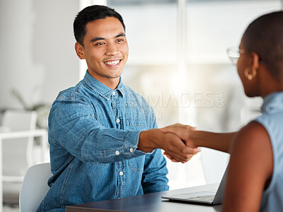 Two cheerful businesspeople shaking hands in a interview together at work. Happy colleagues greeting with a handshake in an office. Asian male boss promoting a black female employee