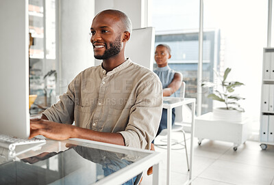 Buy stock photo Young happy african american businessman using a desktop computer in an office at work. Content male businessperson typing an email at a desk. Business professional working on a computer