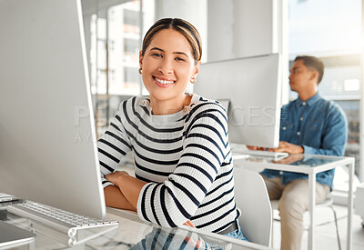 Buy stock photo Portrait of a young mixed race businesswoman using a desktop computer in an office at work. Happy hispanic female businessperson smiling while sitting at a desk. Business professional working on a computer