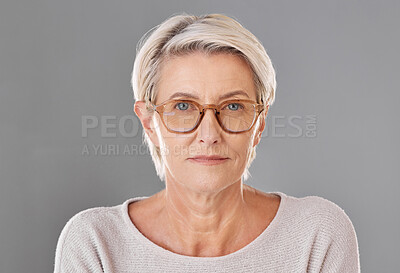 Buy stock photo One mature caucasian woman wearing trendy brown prescription spectacles against a grey copyspace studio background. Senior female looking serious wearing reading glasses for better eyesight