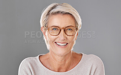 Buy stock photo Portrait of one beautiful caucasian mature woman isolated against a grey studio background wearing glasses. Senior woman smiling and showing her bright dentures in a studio