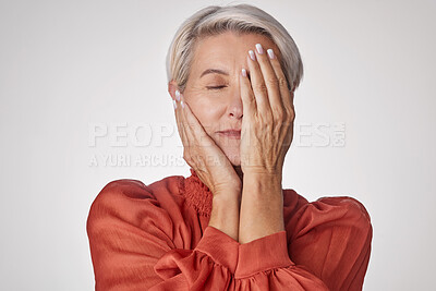 Buy stock photo One mature woman suffering with a headache and looking stressed while posing against a grey copyspace background. Ageing woman experiencing anxiety and fear in a studio