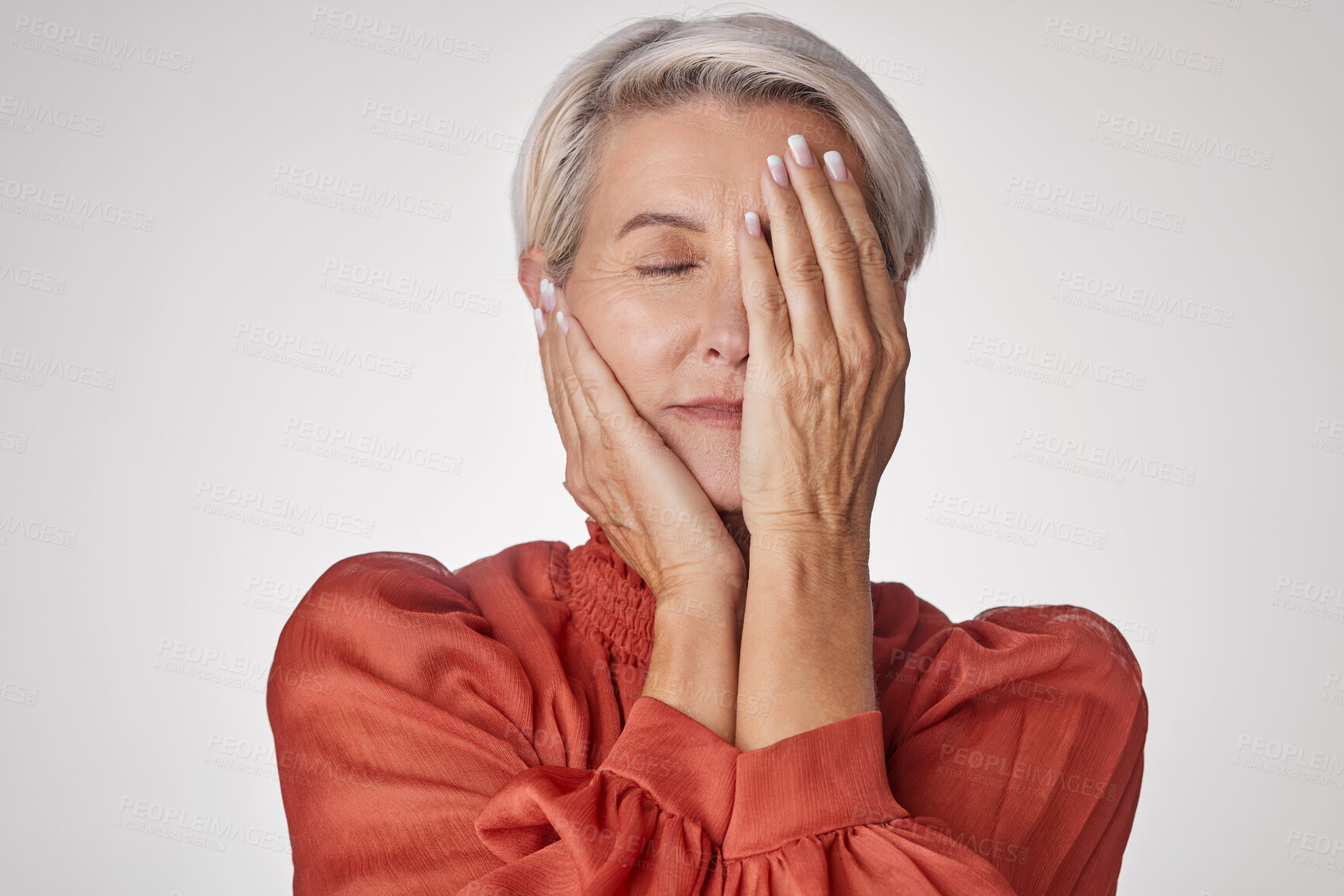 Buy stock photo One mature woman suffering with a headache and looking stressed while posing against a grey copyspace background. Ageing woman experiencing anxiety and fear in a studio