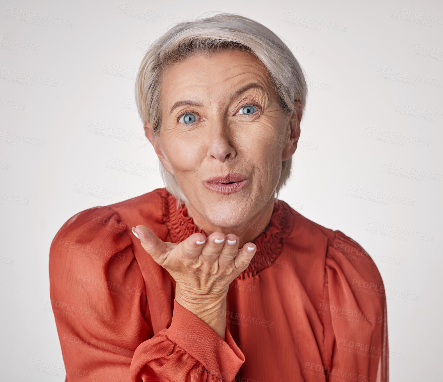 Buy stock photo One happy mature caucasian woman blowing a kiss with her hands against a grey background. Ageing female using body language to express love, kindness, flirting and affection with a gesture